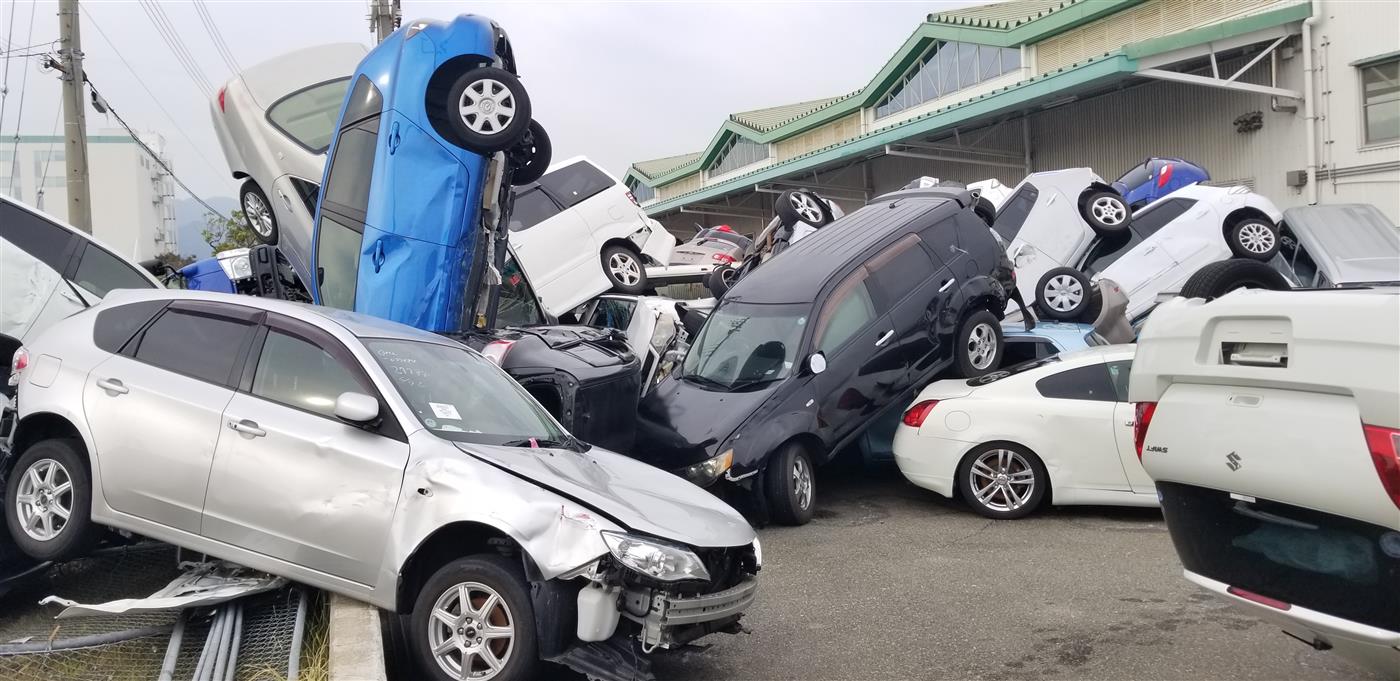 Export vehicles piled on top of each other against a storage building after Typhoon Jebi